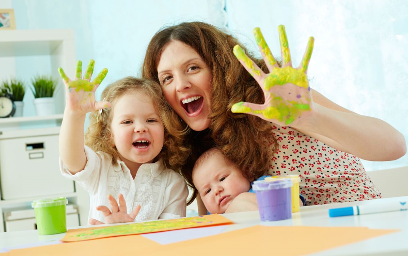 A mother and two daughters playing with paint.