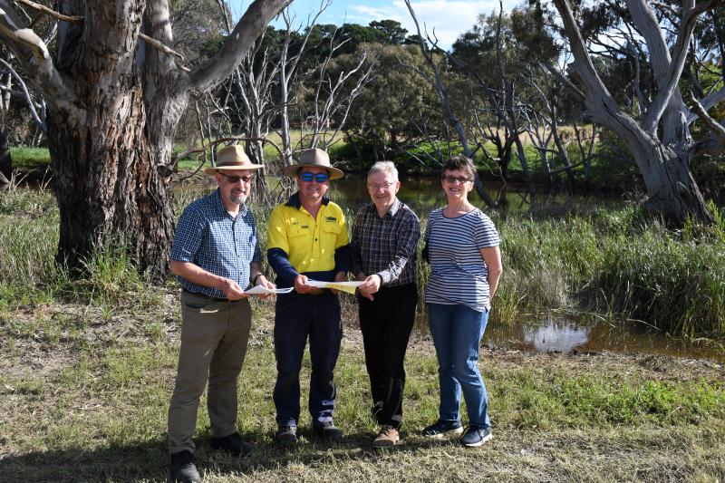 Four people looking at plans standing in front of the Moorabool River.